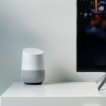 white and gray Google smart speaker beside black flat screen TV