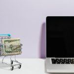 laptop and shopping cart with paper bills